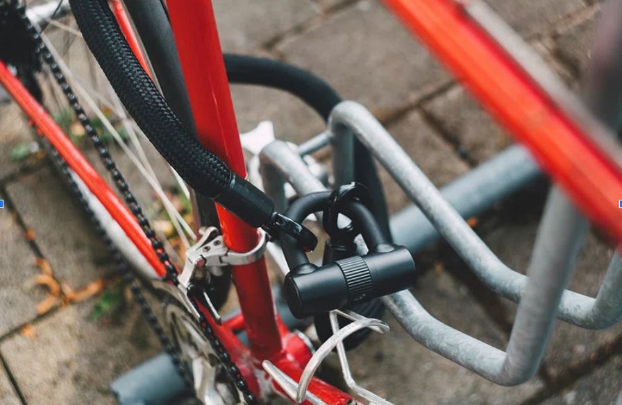 Vélo électrique attaché avec un cadenas en U dans un stationnement urbain.